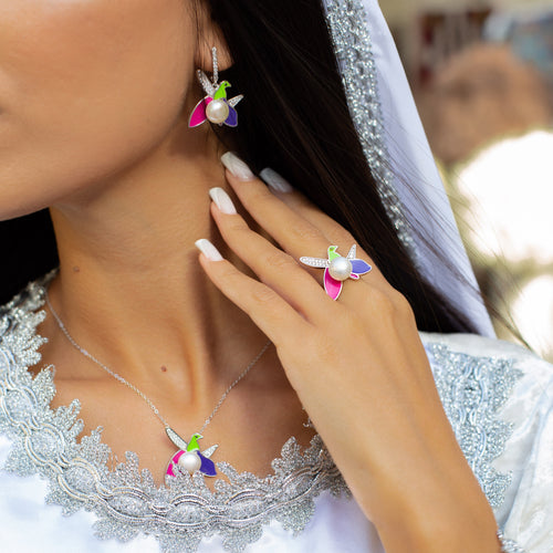Close-up of a woman wearing colorful earrings and a ring, with a blurred background.