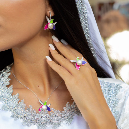 Close-up of a woman wearing colorful earrings and a ring, with a blurred background.