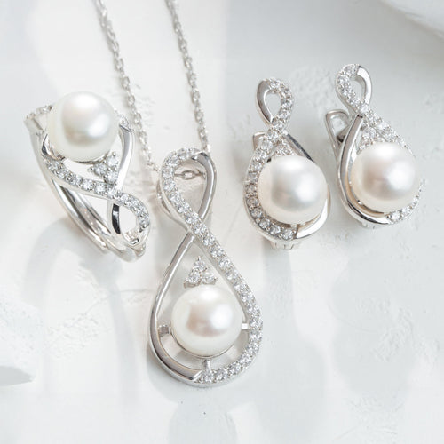 Pearl jewelry set with necklace, earrings, and ring on a white background