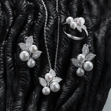 Qalereya görüntüsünə şəkil yükləyin, Pearl jewelry set including necklace, earrings, and ring on a textured black surface.
