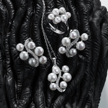 Qalereya görüntüsünə şəkil yükləyin, Pearl jewelry set including necklace, earrings, and ring on a dark textured surface
