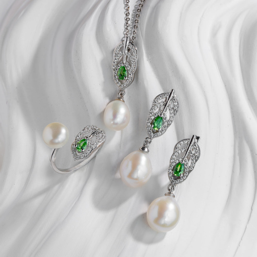 Pearl jewelry set with green gemstones on a white fabric background
