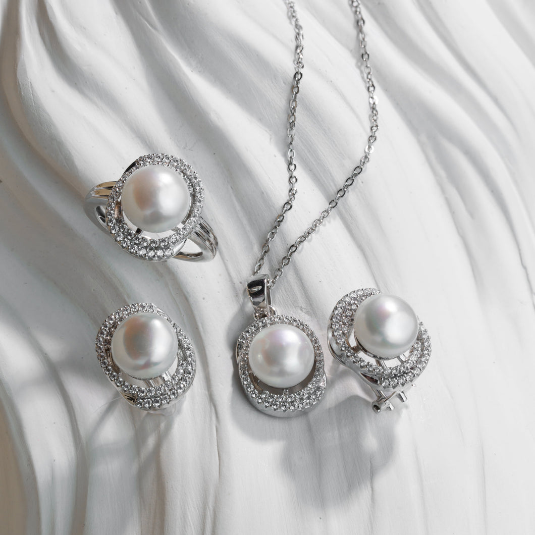 Pearl jewelry set with necklace, ring, and earrings on a white fabric background
