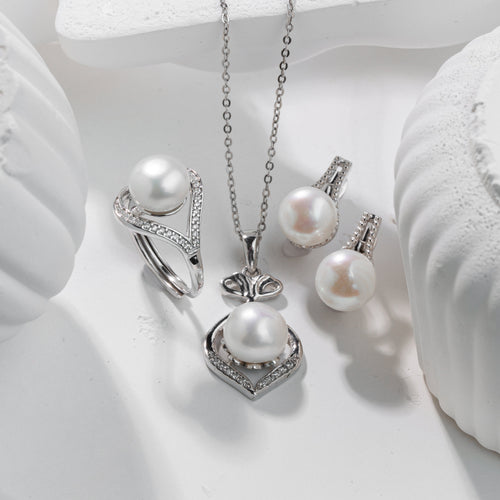 Pearl jewelry set with necklace, earrings, and ring on a white surface