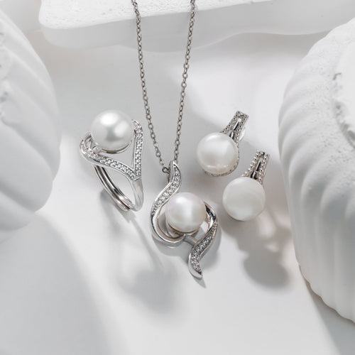Pearl jewelry set including necklace, ring, and earrings on a white surface.