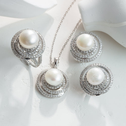 Pearl jewelry set with silver rings and necklace on a white background
